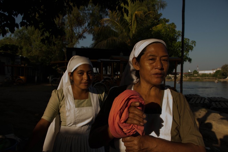 Two evangelical women from Guatemala serve free coffee and atole to people crossing the Suchiate River. Photo by Gabriela Bortolamedi.
